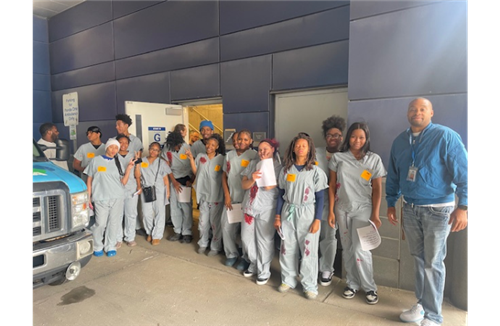 A group of Henry Ford High School students dressed in gray scrubs with simulated blood